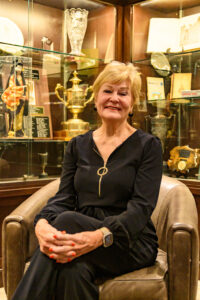 Woman seated in a leather chair in front of a trophy case